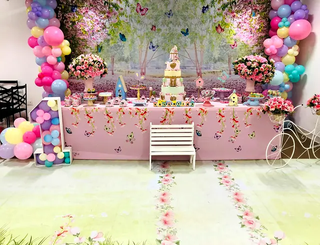 Mesa de festa com tema de jardim encantado, flores, balões e caminho de pétalas