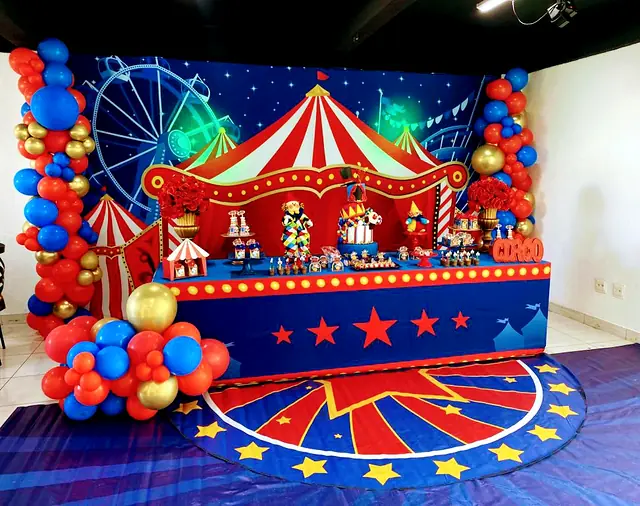 Mesa de festa com tema de circo, lona vermelha, balões e tapete de estrelas